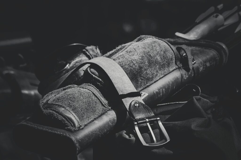 Detailed black and white image of a leather archery quiver with buckle, emphasizing texture and craftsmanship.
